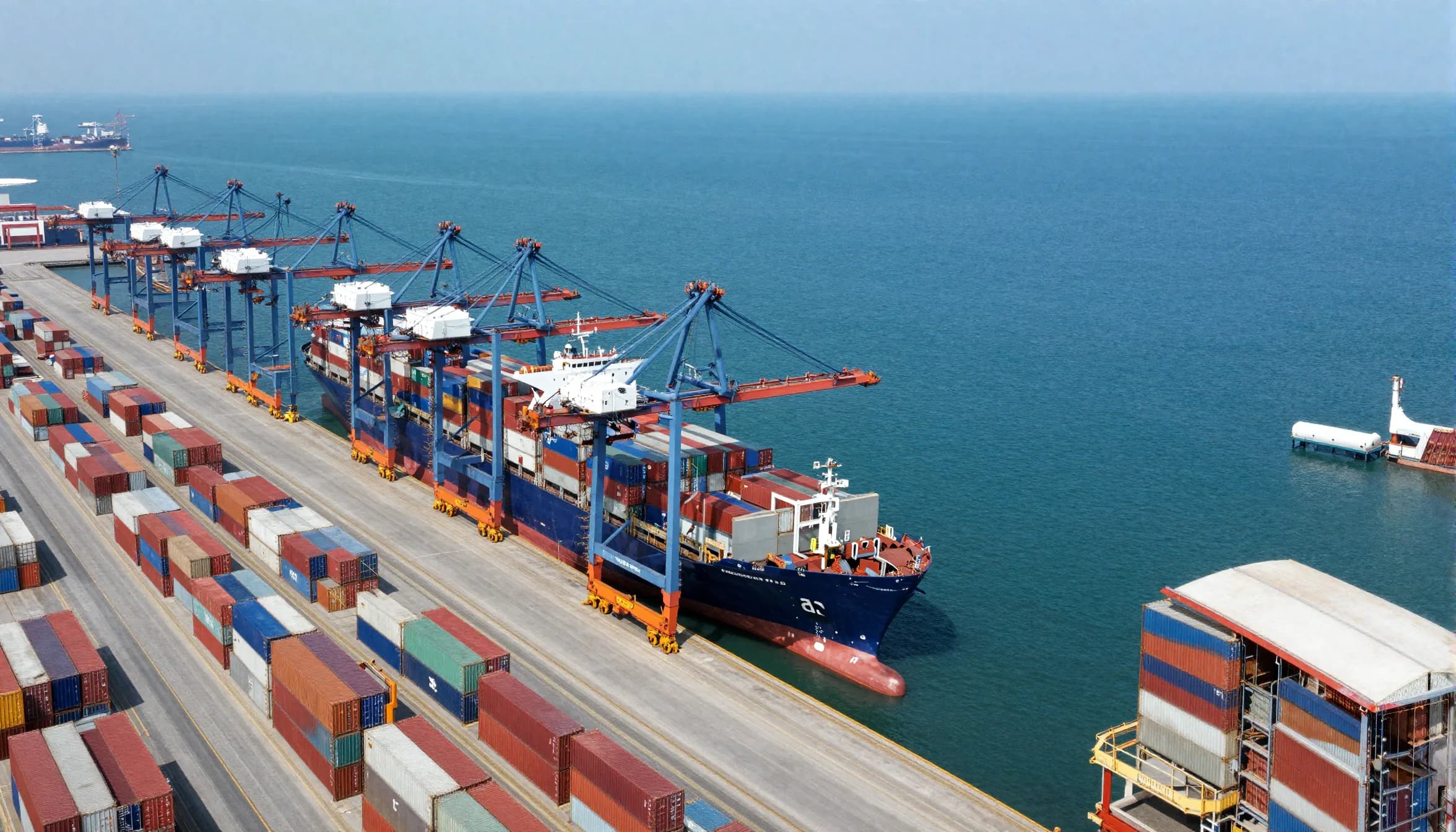 Aerial view of a container port terminal with gantry cranes loading a cargo ship